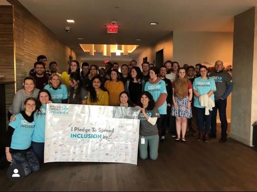 group of Brightspot employees standing with signed Spread the World for Inclusion sign
