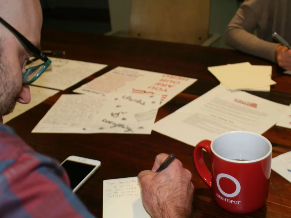 Brightspot employees writing letters of thanks to service members during volunteer event