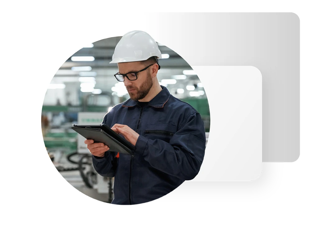 Photo of a worker wearing a hard hat and holding a tablet device in a manufacturing workplace