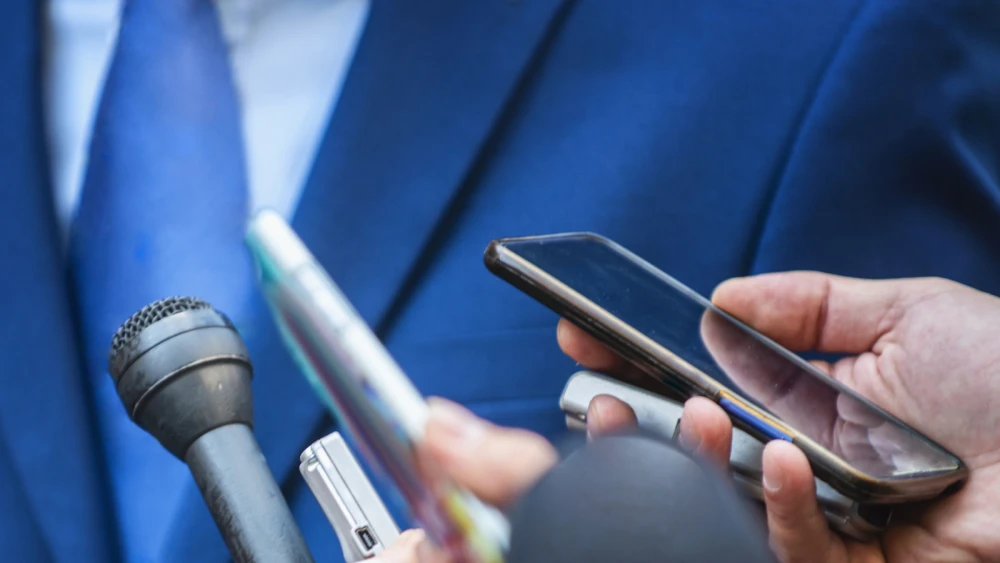 image of news reporters holding microphones and recording devices during an interview
