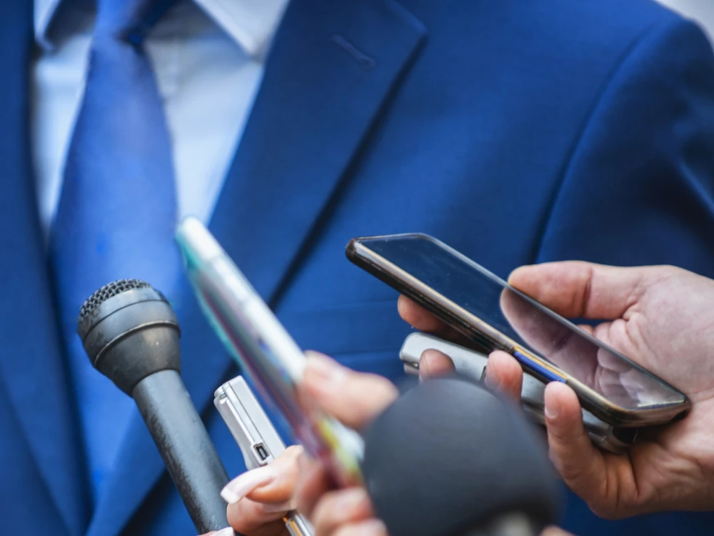 image of news reporters holding microphones and recording devices during an interview
