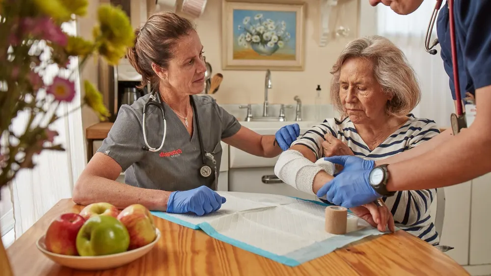 image of DispatchHealth nurses assisting elderly patient at home